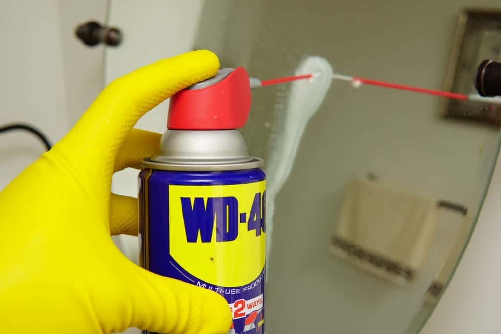 spraying wd40 on shower glass to clean it