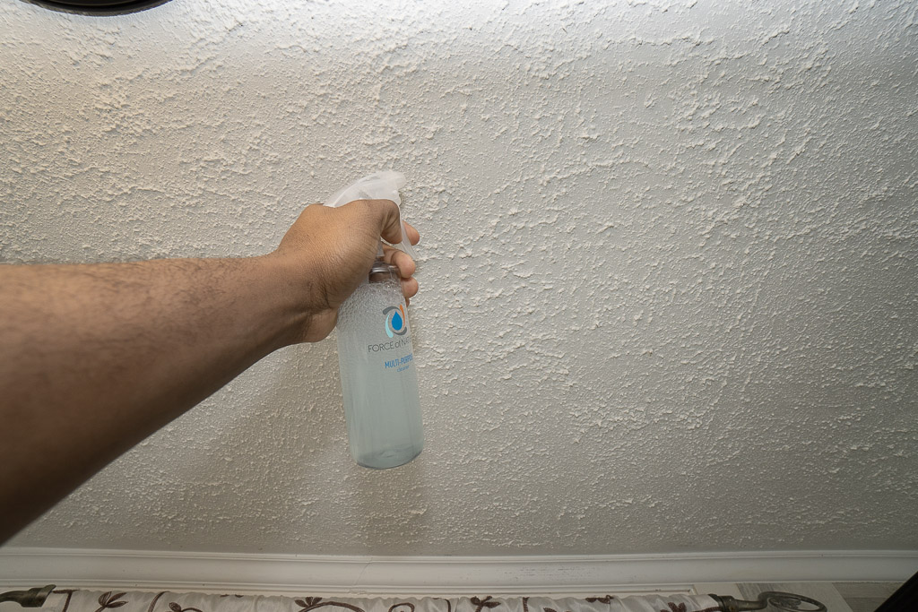 spraying cleaning solution on popcorn ceiling