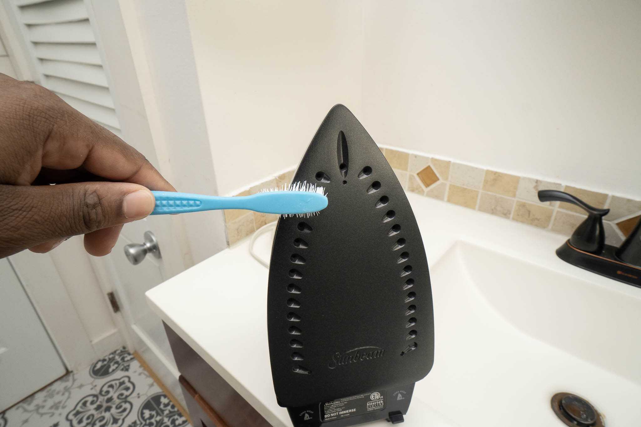 Cleaning holes on iron bottom with toothbrush