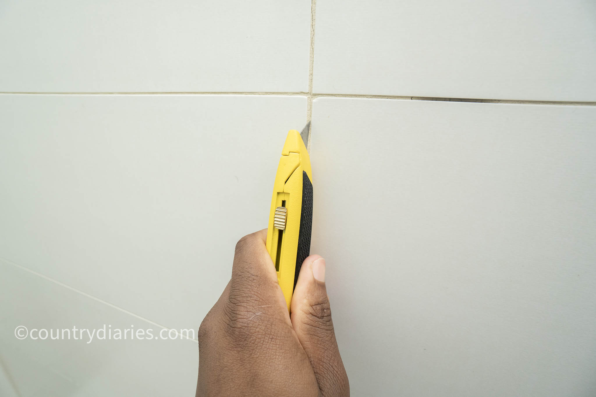using knife to remove grout from joint