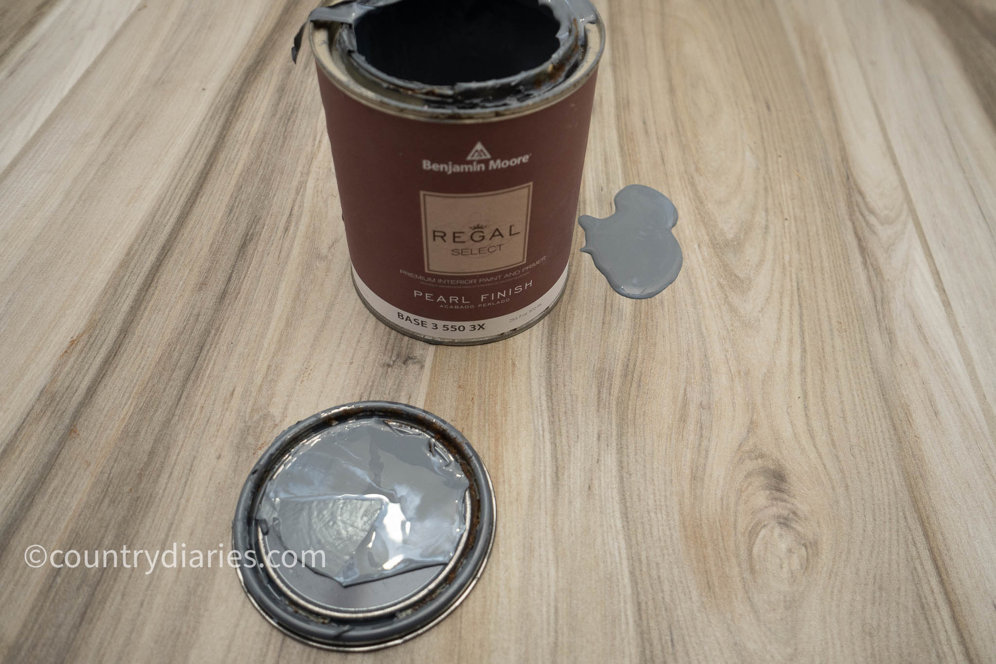 regal select can of paint opened with some poured on the floor tiles